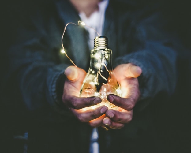 A man holding a lit light bulb.